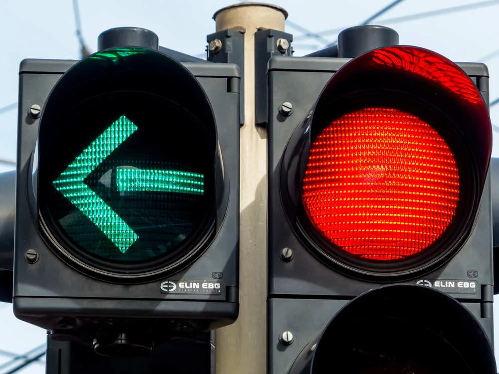 a traffic light with retoem light. green light for traffic turning left.